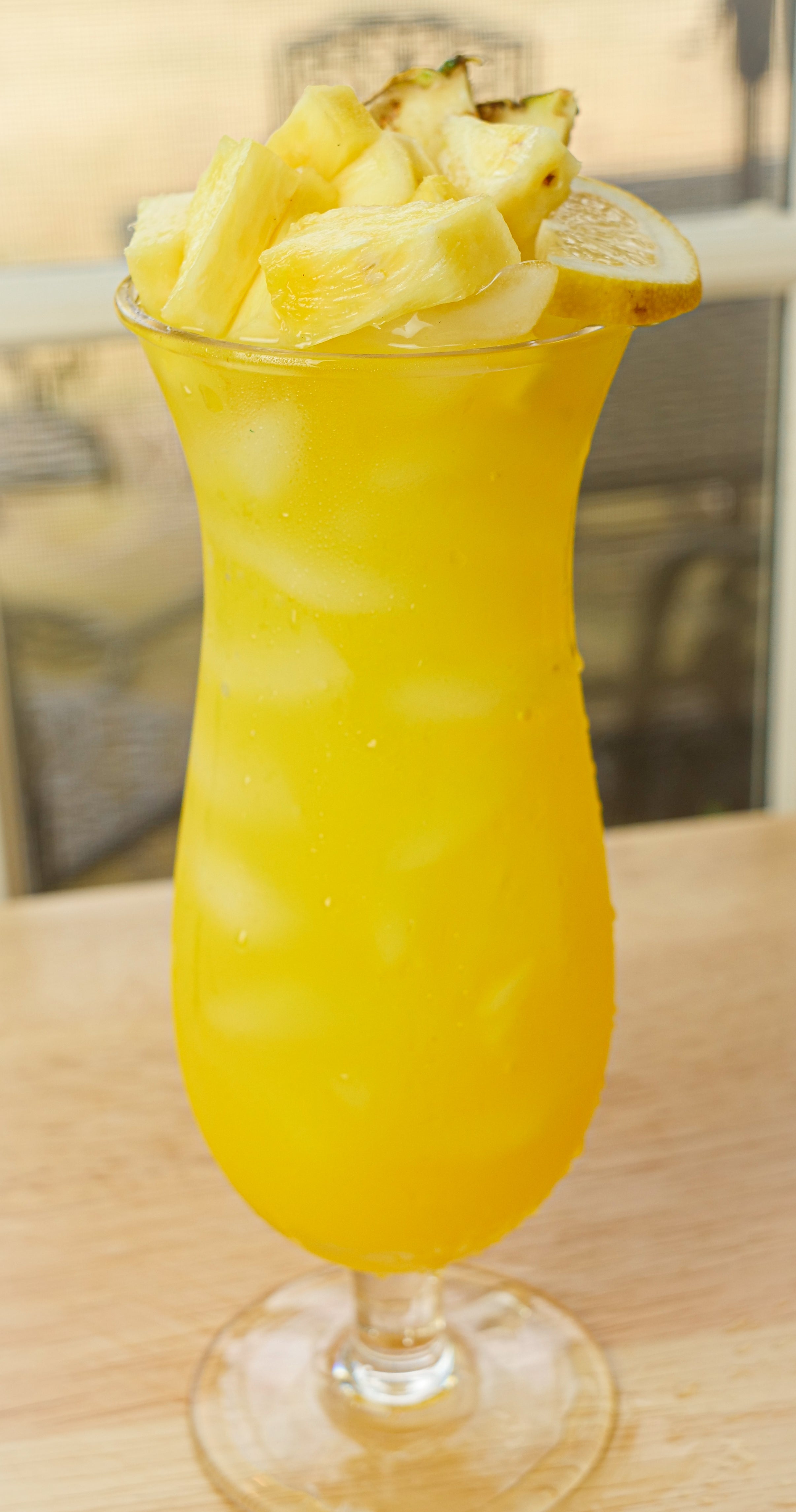 Igotchu Pineapple Lemonade juice in a clear glass, showcasing vibrant yellow color with fresh pineapple and lemon slices.