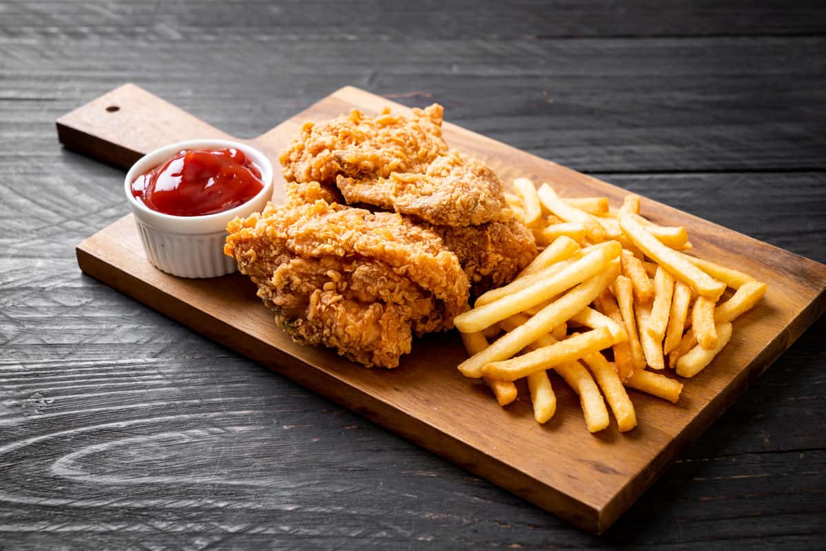 Igotchu Seasonings fried chicken and fish coating mix on a plate with French fries, showcasing crispy, seasoned fried food.