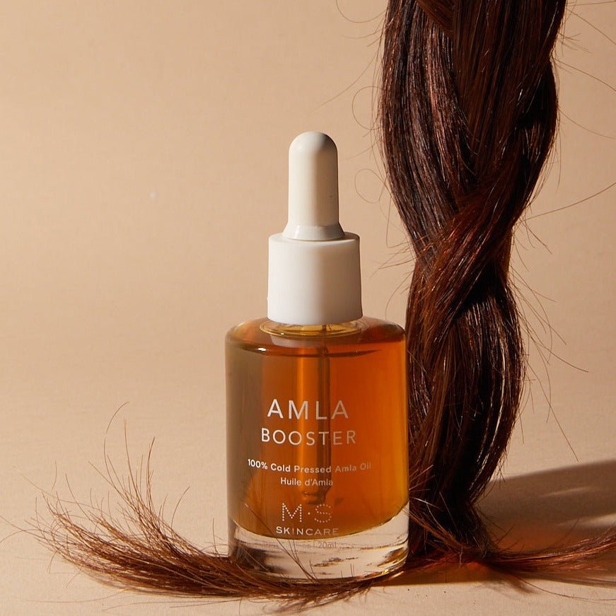 Bottle of M.S Skincare Amla Oil, an Ayurvedic oil for hair and skin, with amber-colored liquid in a clear glass bottle.