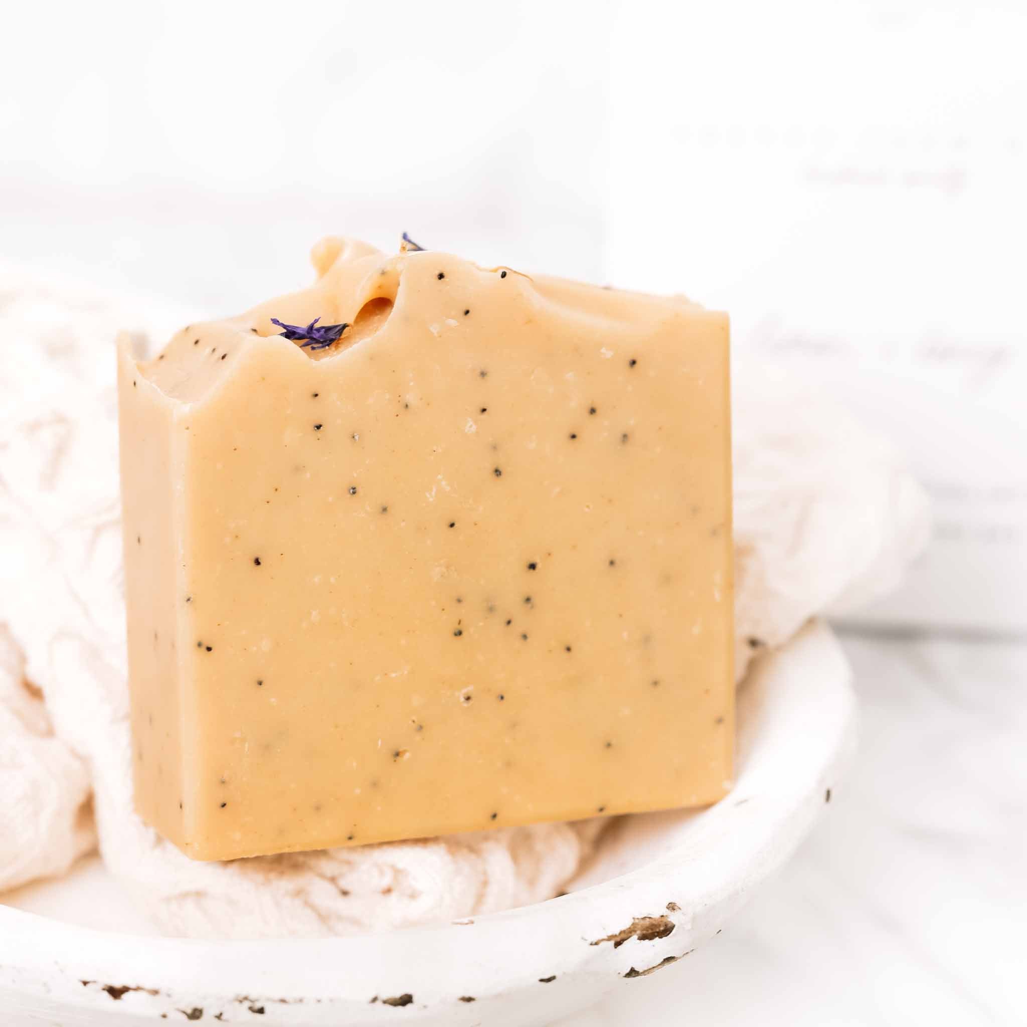 Handmade lemon, honey, and poppy seed goat milk soap bar by Pretty Farm Girl, featuring a natural, textured soap with lemon slices.