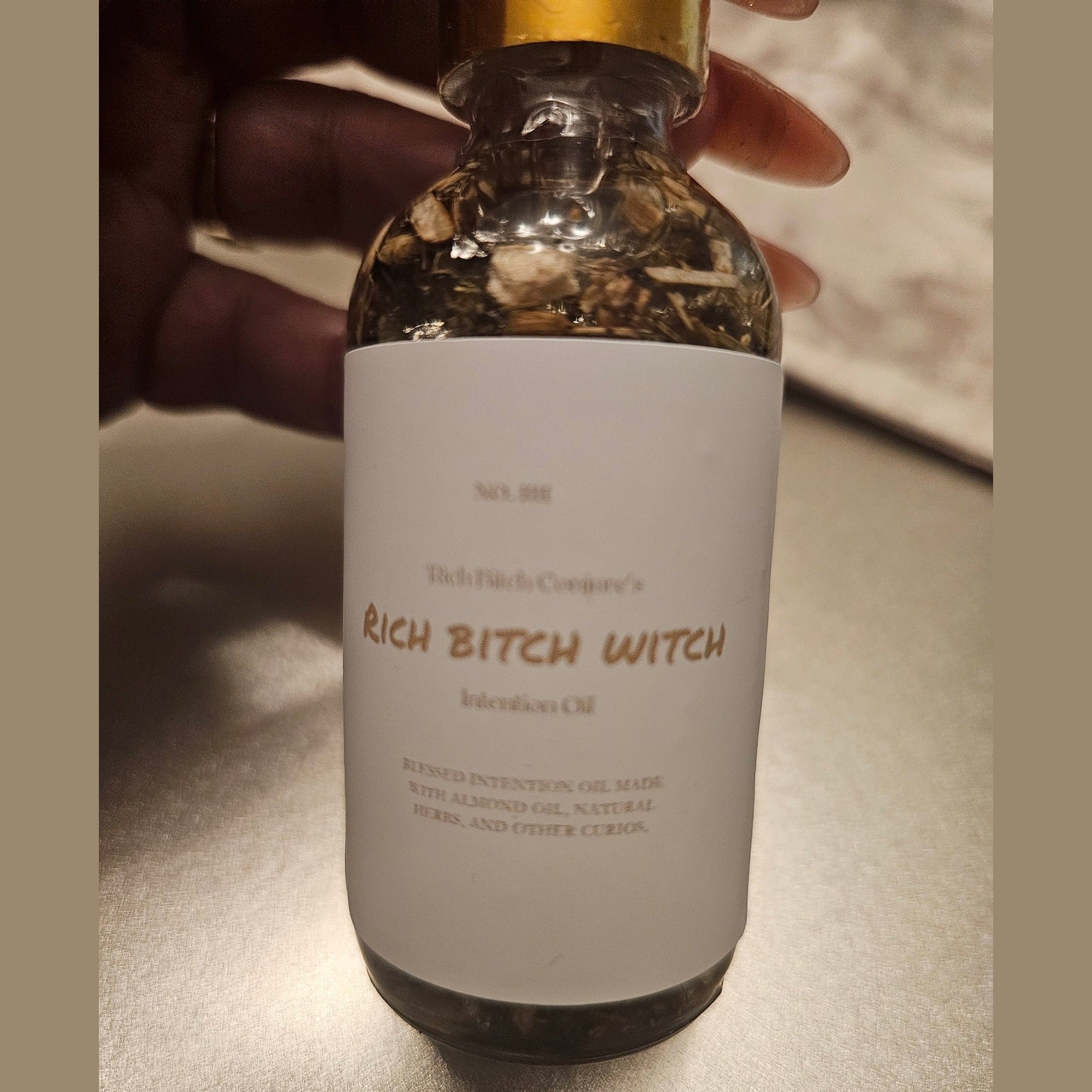 Rich Bitch Conjure Hoodoo Oil bottle labeled "Rich Witch Bitch" with dark liquid inside and decorative label.
