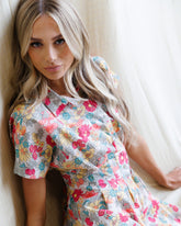 Downeast pleated shirtdress with long sleeves, button front, and waist tie, shown on a model in a casual outdoor setting.