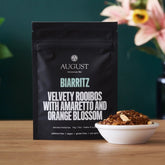 Biarritz Orange Amaretto Rooibos Tea by August Uncommon Tea, caffeine-free herbal tea in a cup with vibrant orange and amber colors.