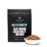 Cup of Cult of Demeter Cocoa Anise Barley Herbal Tea by August Uncommon Tea, showcasing brewed tea in a clear glass cup.
