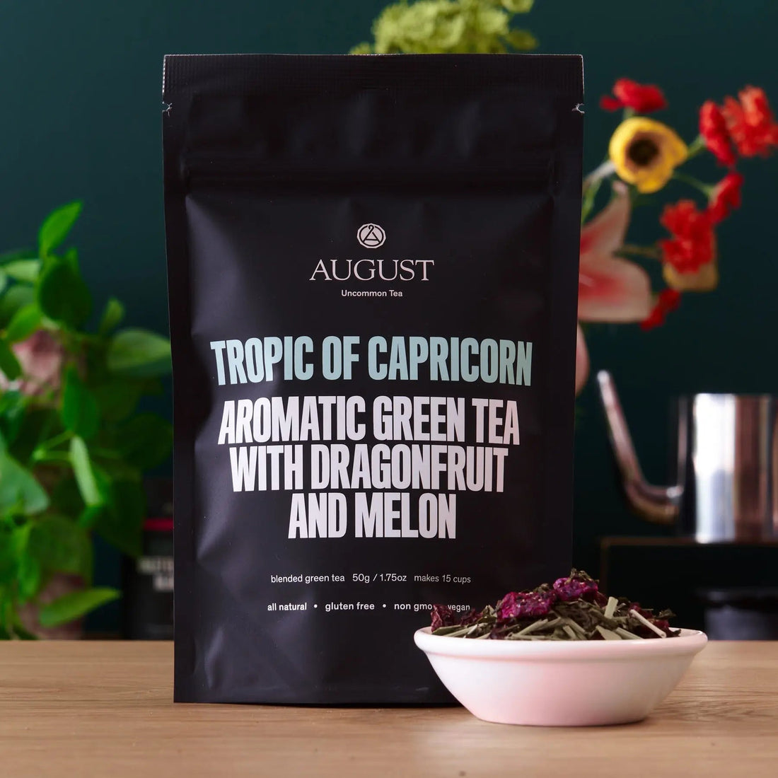 Green tea bag of Tropic of Capricorn Dragonfruit Melon flavor by August Uncommon Tea, shown with the tea packaging and branding.