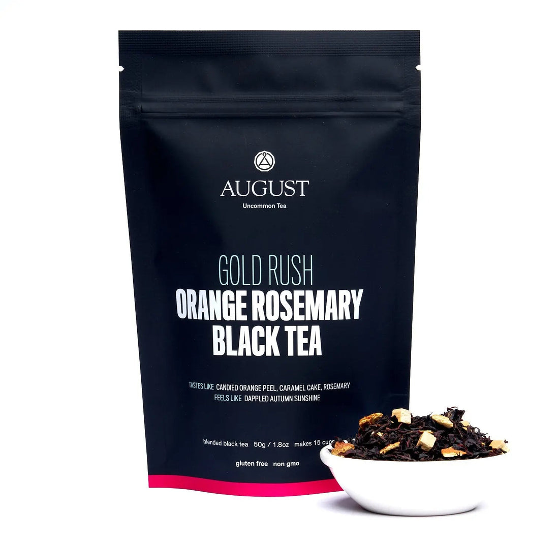 Gold Rush Orange Rosemary caramel black tea in a tea bag, from August Uncommon Tea, with vibrant orange and herbal notes.