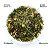 Neon Forest Apple Chamomile Green Tea by August Uncommon Tea, featuring fresh green tea leaves and chamomile flowers.