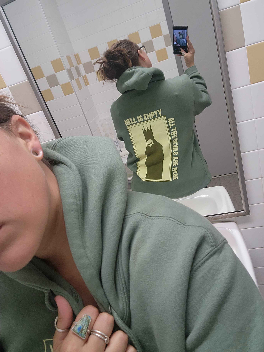 Sage green hoodie featuring "Hell is Empty" text design from Any Means Necessary Clothing, casual pullover style with hood and front pocket.