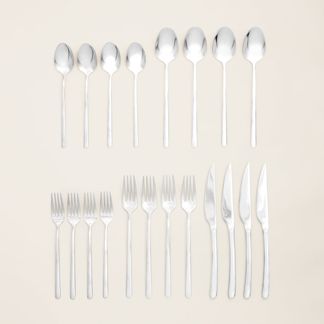 Italic Emilia 20-piece flatware set including forks, knives, spoons, and teaspoons arranged on a white background.