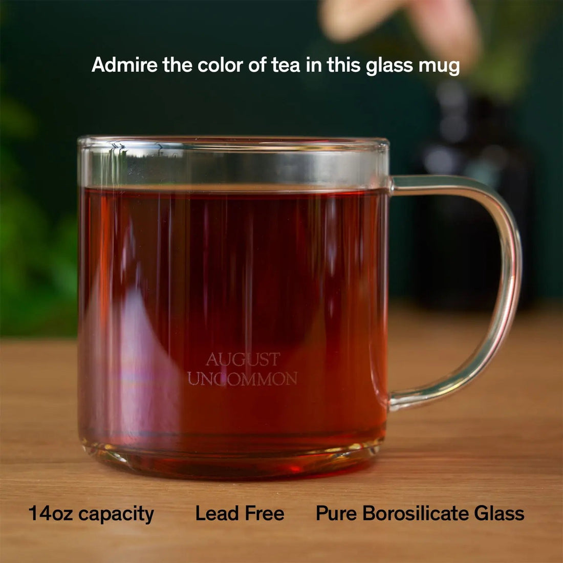Clear glass mug from August Uncommon Tea, showcasing elegant teaware design with a smooth handle and transparent body.