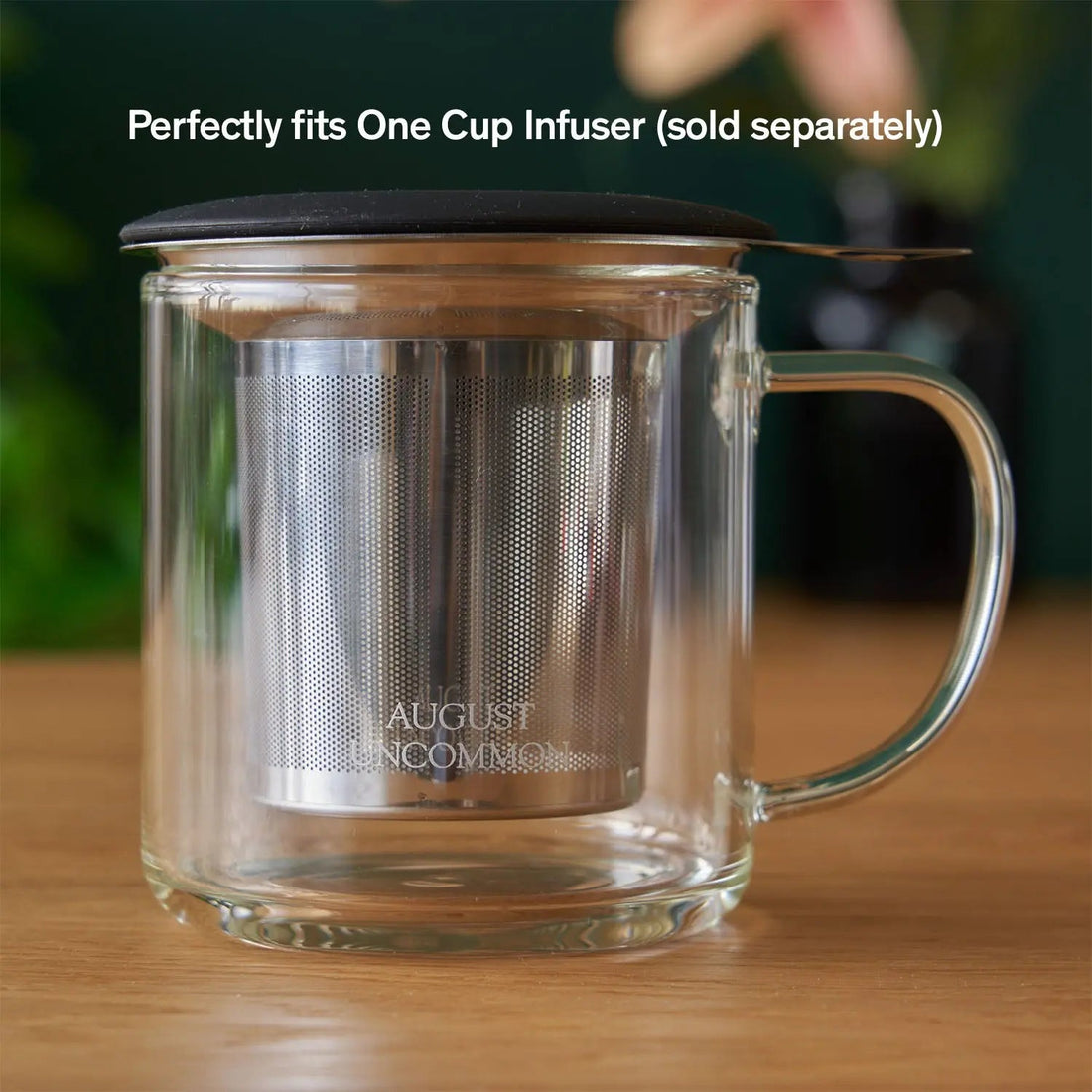 Clear glass mug from August Uncommon Tea, elegant teaware with a smooth handle and transparent design for enjoying hot beverages.