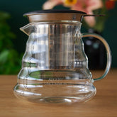Two cup glass teapot from August Uncommon Tea, clear teaware with a sleek design, perfect for brewing and serving tea.