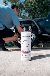 Blackline Car Care BLACKLINE® Blackout Trim & Tire Dressing applied to car tires and trim for a sleek, shiny appearance.