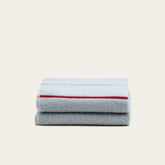 Soft beige Deia Australian Cotton Towels from Italic, shown in a cozy home bed setting with textured fabric details.