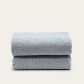 Soft white Deia Australian cotton towel from Italic, displayed on a bed, showcasing its plush texture and high-quality fabric.