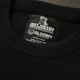 Close-up of the Big Gloomy Knit Sweater from Any Means Necessary Clothing showing its textured, dark-colored knitted fabric.