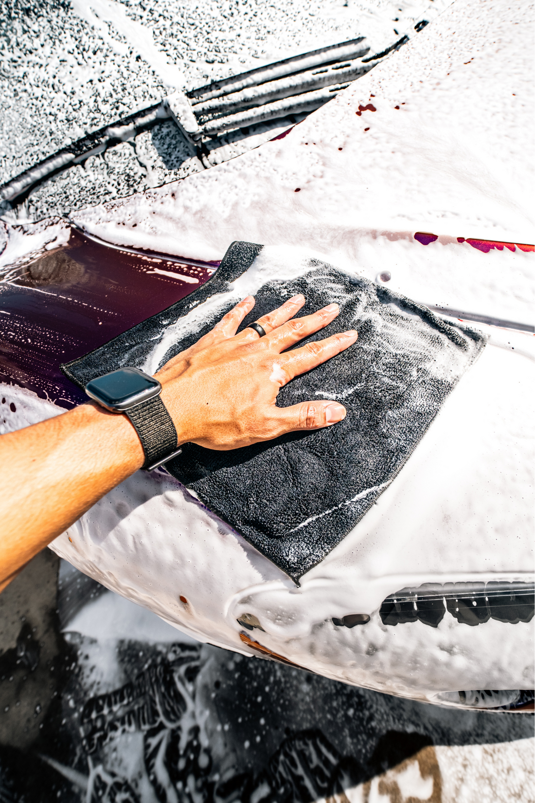 Blackline® synthetic clay towel in use on car surface for detailing and removing contaminants, black and textured fabric.