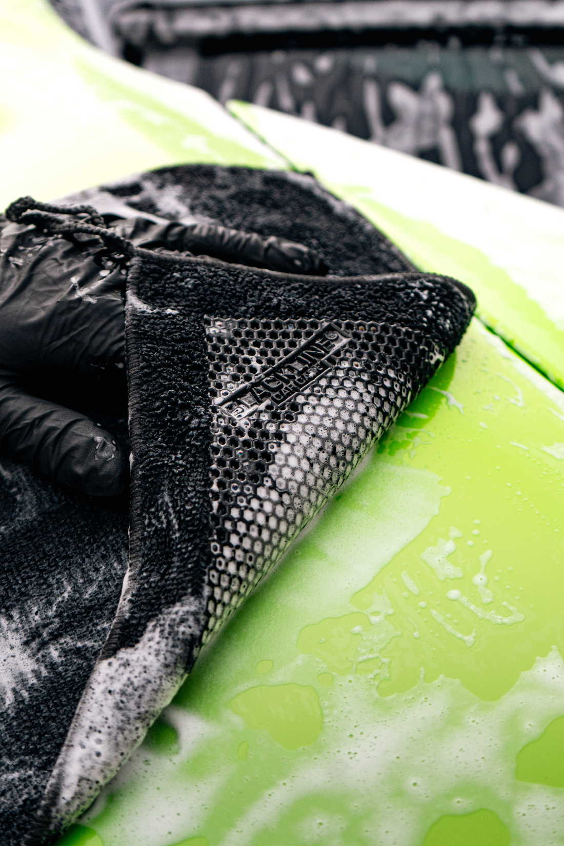 Blackline synthetic clay towel in black for car detailing, shown on a McLaren sports car for smooth, scratch-free surface cleaning.