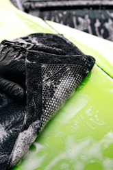 Blackline synthetic clay towel in black for car detailing, shown on a McLaren sports car for smooth, scratch-free surface cleaning.