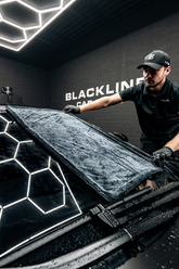 Blackline Car Care twisted-loop drying towel draped over a car windshield, demonstrating its soft, absorbent microfiber texture.