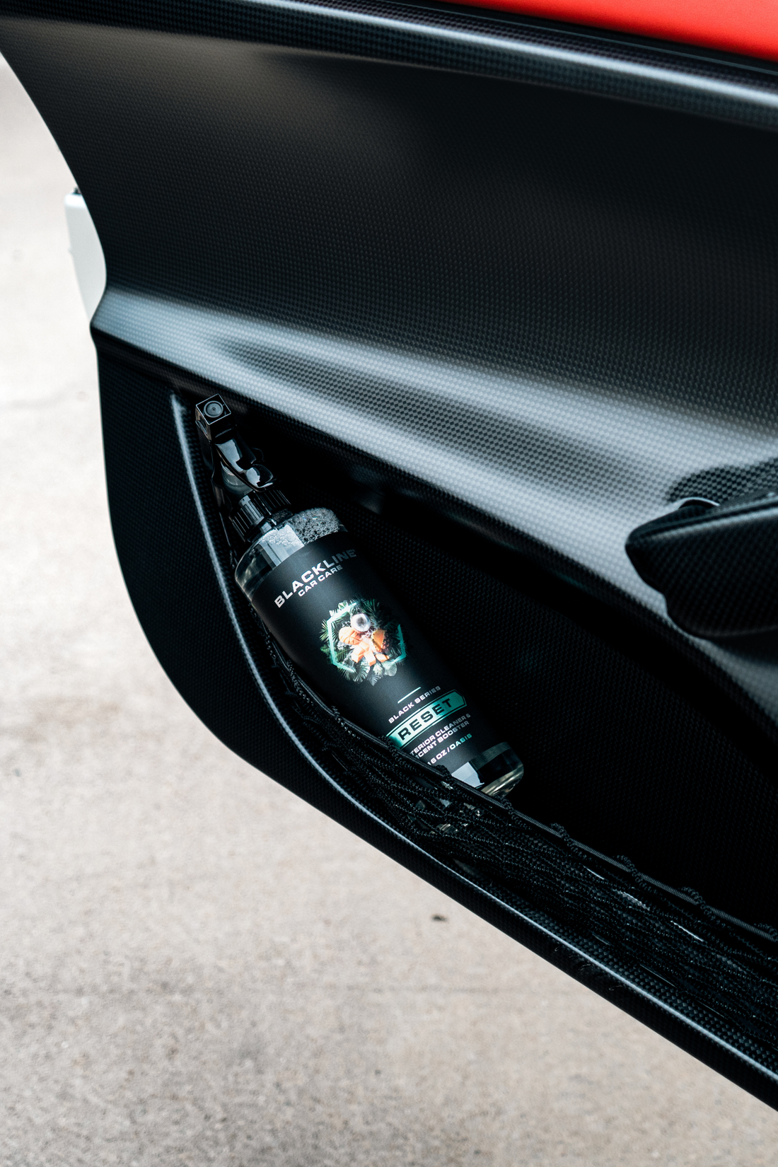Blackline Car Care BLACKLINE® RESET interior cleaner and scent booster applied to a car door panel.