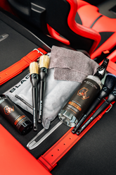 Blackline Reset Interior Cleaner and Scent Booster in a Ferrari F12 trunk, showing the product bottle with teakwood scent.