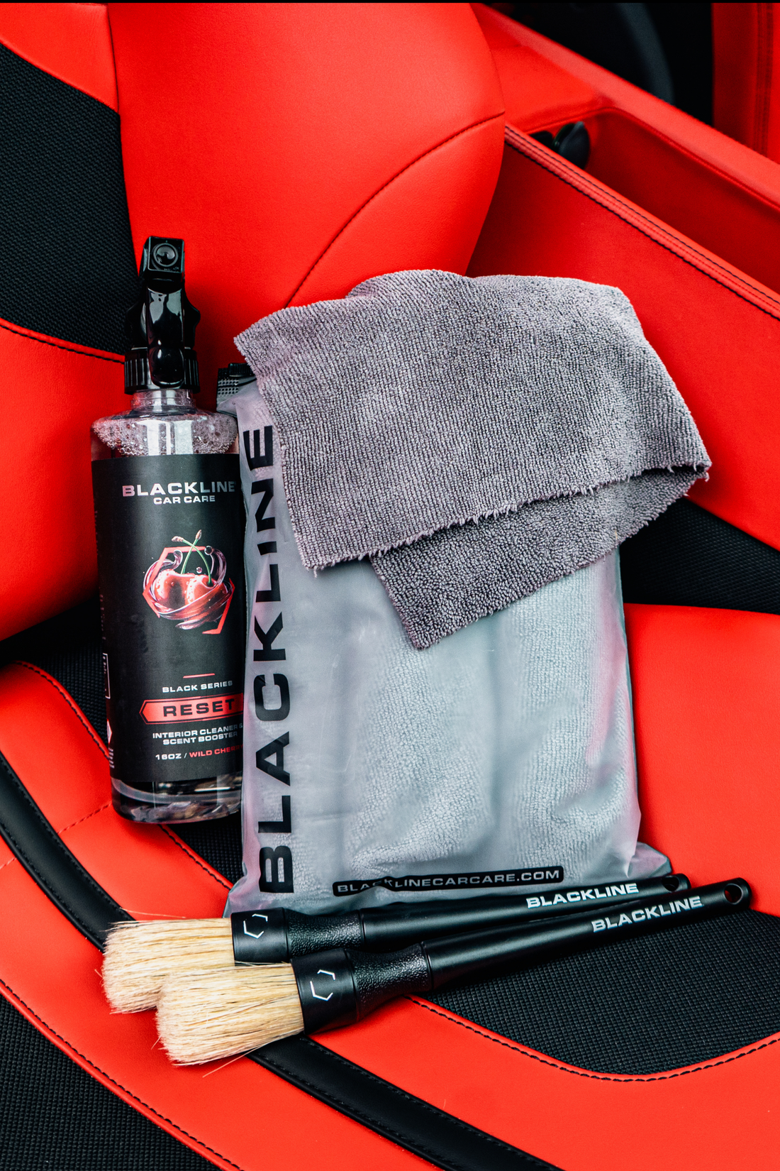 Blackline Car Care BLACKLINE® RESET interior cleaner and scent booster bottle on a Ferrari F12 seat, showcasing car interior cleaning products.