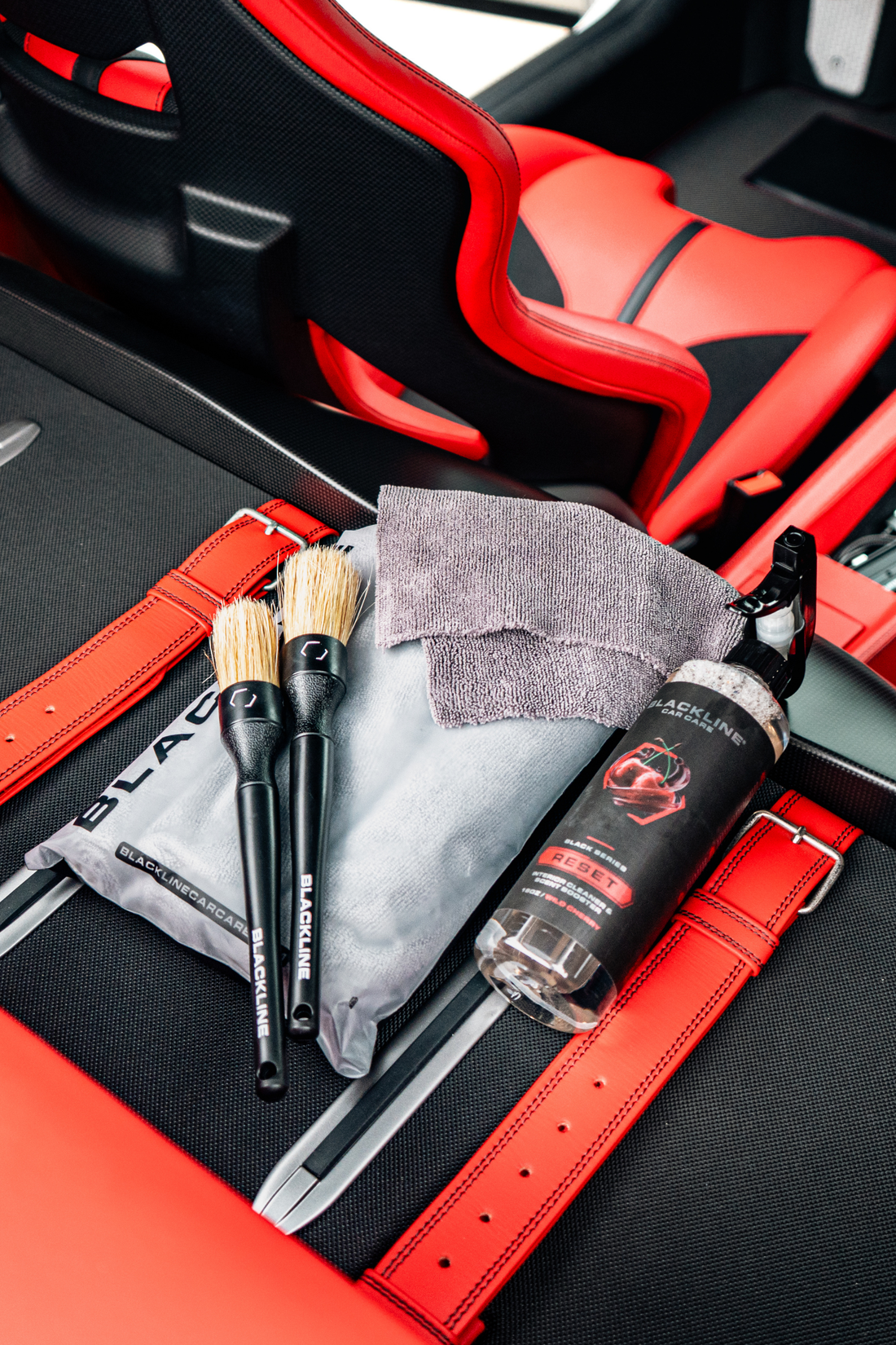 Blackline RESET interior cleaner and scent booster bottle in Ferrari F12 trunk, showcasing Blackline Car Care product with wild cherry scent