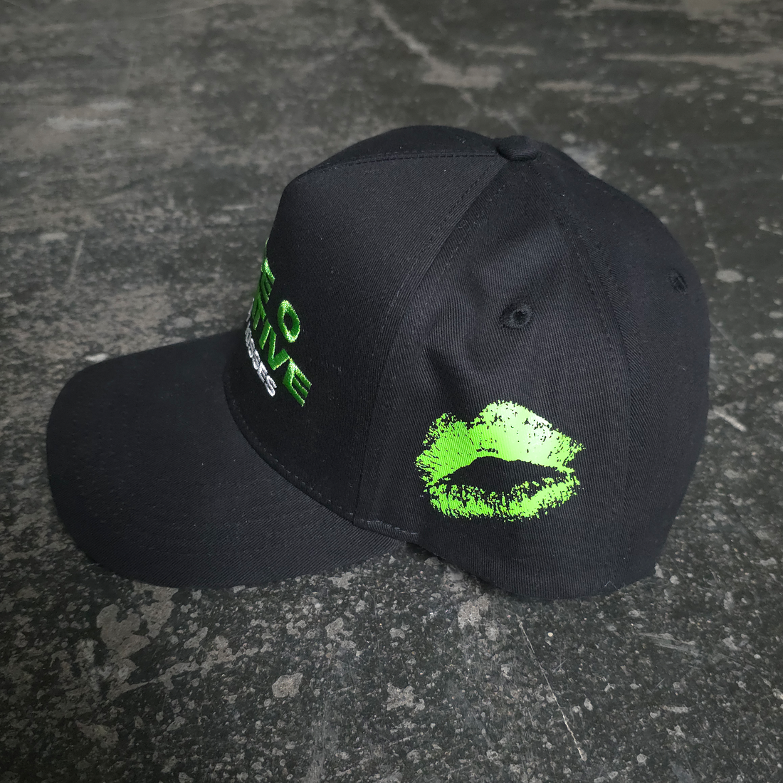 Black Bloody Kisses hat by Any Means Necessary Clothing featuring a bold graphic design and adjustable strap.