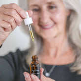 Pretty Farm Girl Brightening Vitamin C Face Serum in a clear glass bottle with dropper, showcasing vibrant orange liquid.