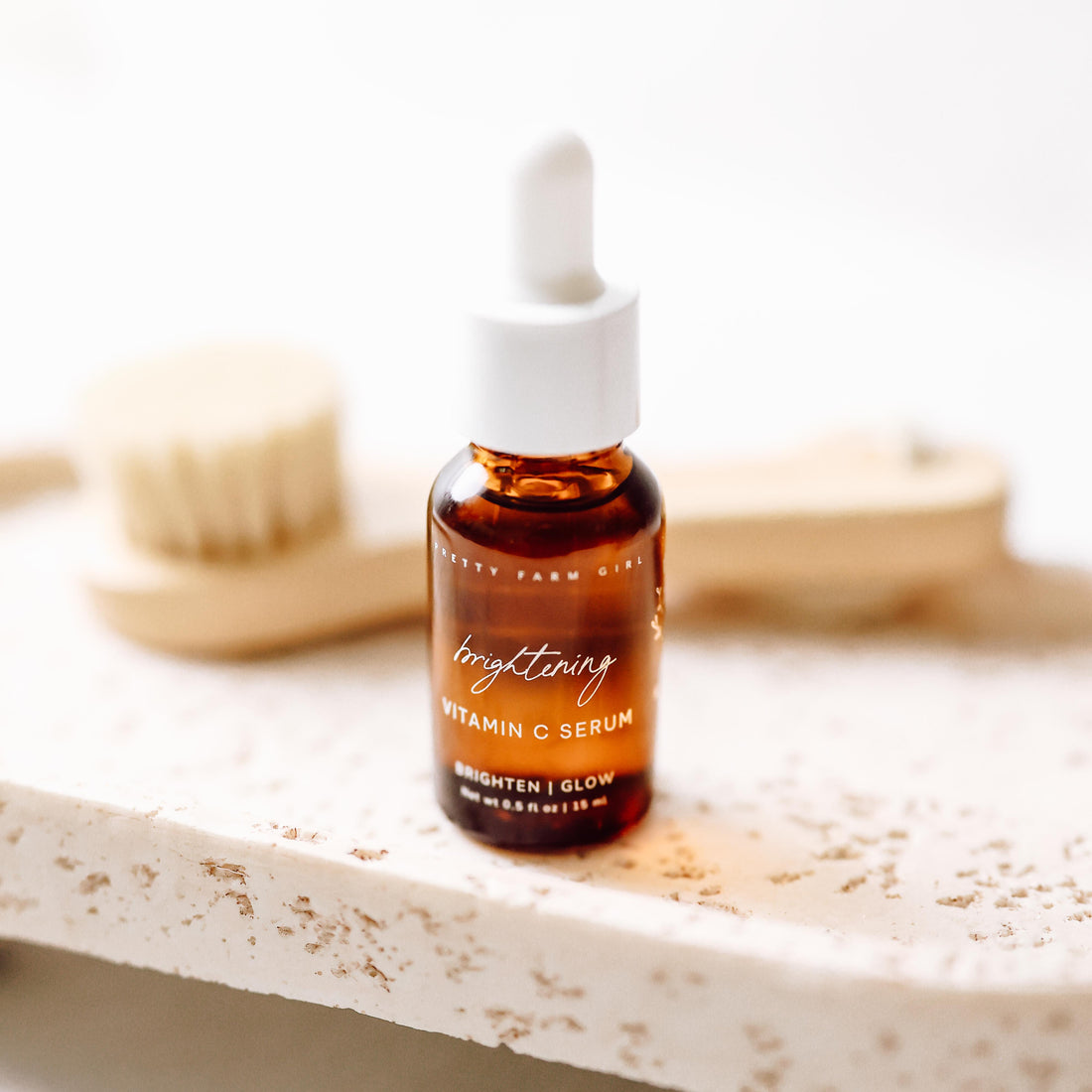 Pretty Farm Girl brightening vitamin C face serum bottle with dropper, showcasing its vibrant packaging and serum texture.