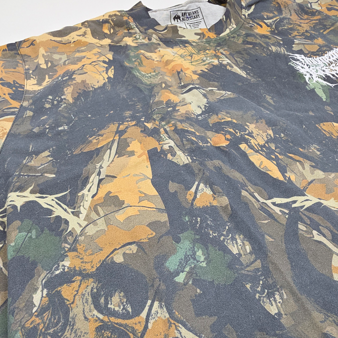 Close-up of Mayhem T-Shirt by Any Means Necessary Clothing featuring a camouflage design and bold graphic print.