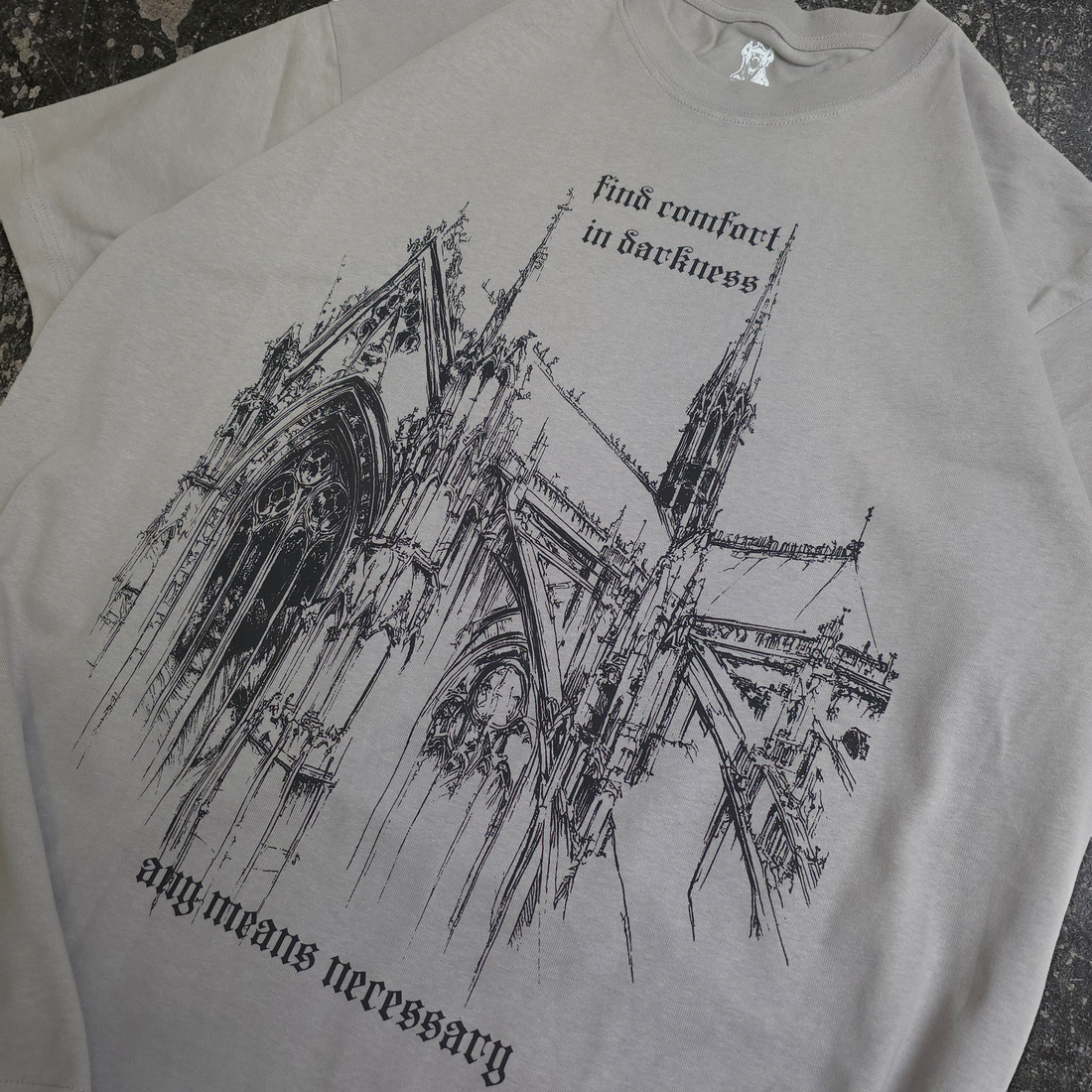 Close-up of a grey Chapel T-Shirt by Any Means Necessary Clothing, showing the front neckline and fabric details.