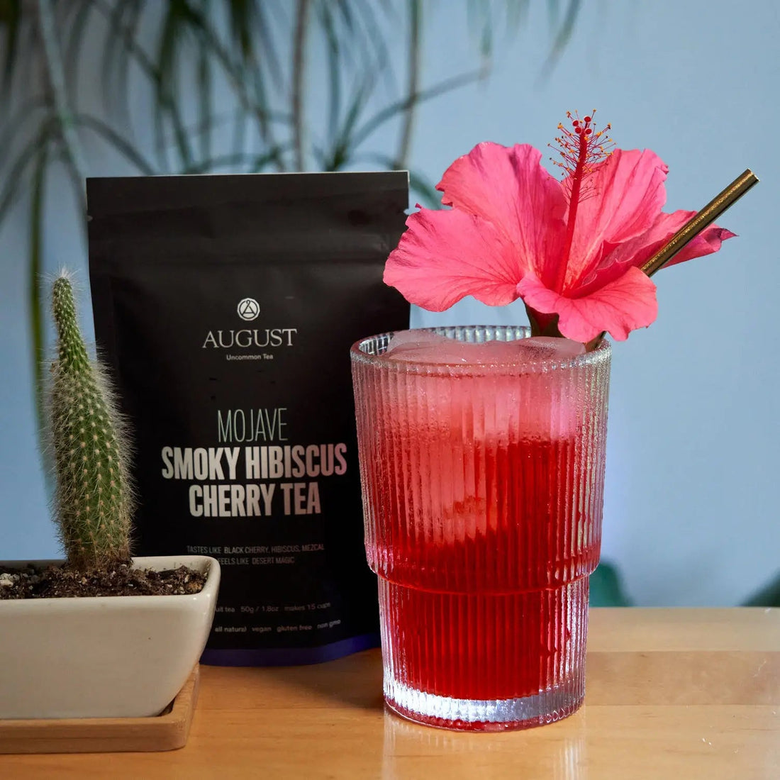 Mojave smoky hibiscus cherry herbal tea in a glass cup by August Uncommon Tea, showcasing vibrant red tea leaves and fresh hibiscus.