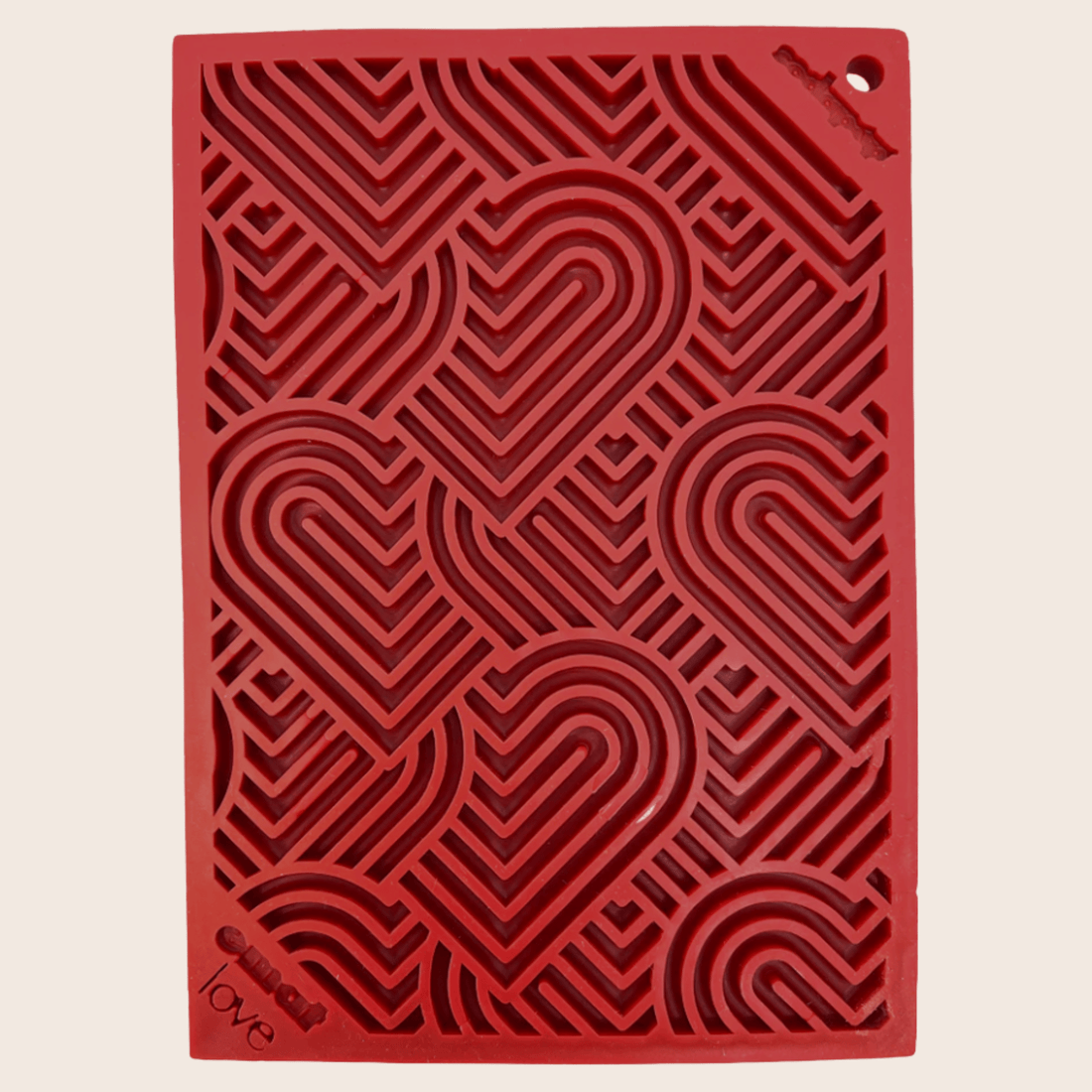 Close-up of Farm To Pet lick mat with red hearts, designed for cats and small dogs to lick and comfort.