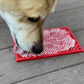 Close-up of Farm To Pet Lick Mat for cats and small dogs, featuring red hearts and a textured surface for licking fun.