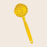 Close-up of Farm To Pet Lick Stick, an interactive dog training toy in yellow with beehive design, for engaging pets.