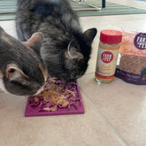 Farm To Pet lick mat for cats and small dogs, beige fishbone design, showing two cats licking the textured surface.