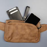Shield Your Body SYB Cross Body Fanny Pack in blue, made from vegan leather, with a phone, keys, and wallet inside.