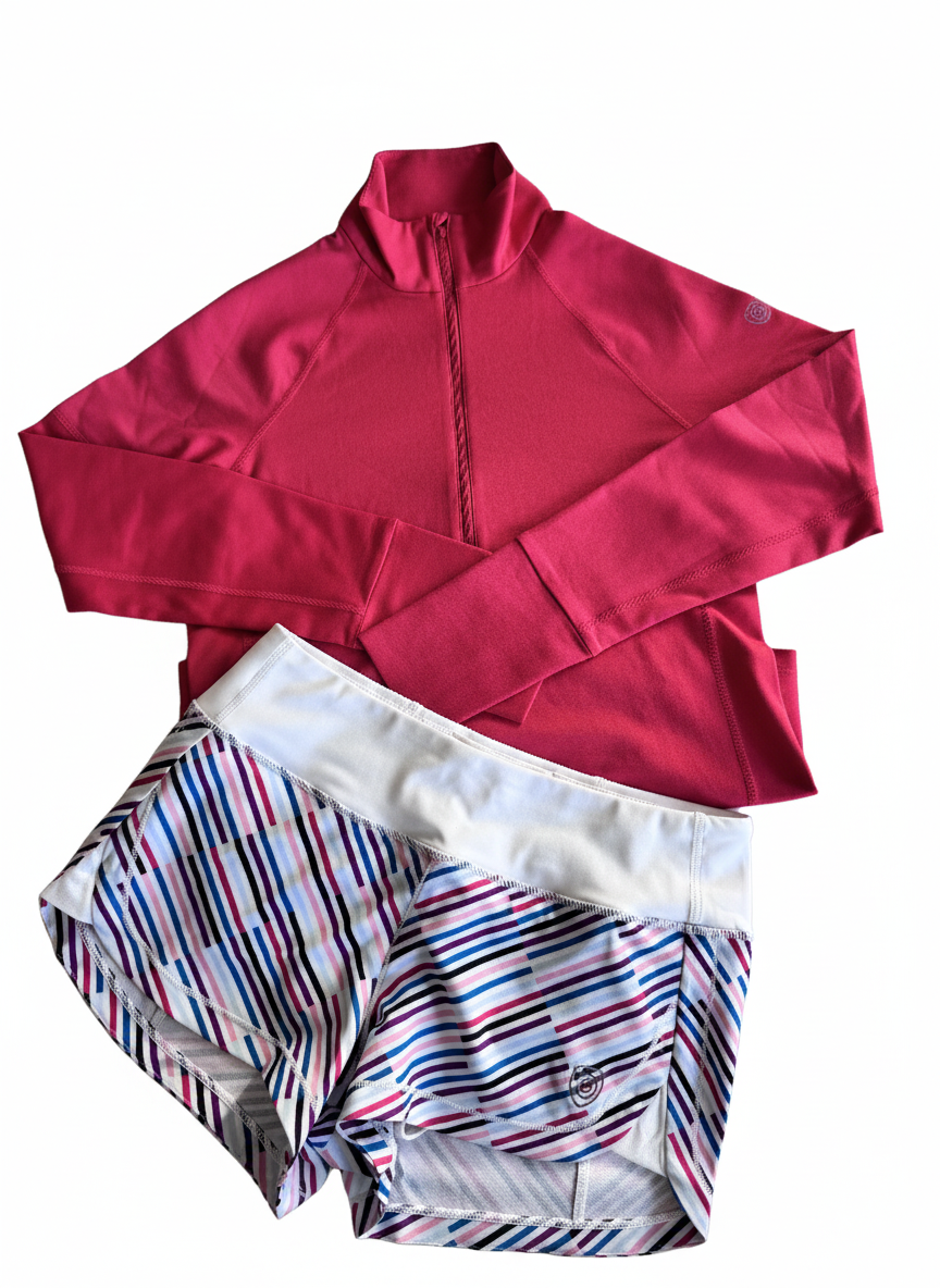 Goal Five Foudy mid-weight long sleeve training top with ½ zip in hot coral, paired with striped shorts.