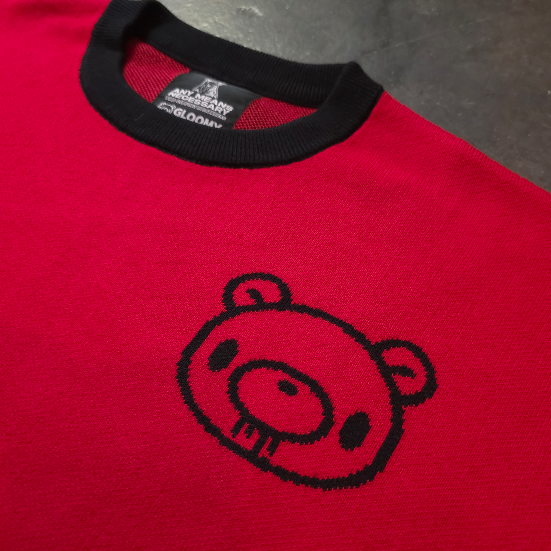 Close-up of the Gloomy Drip Knit Sweater by Any Means Necessary Clothing, showing the textured knit fabric and dark, moody design.