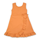 Little girl wearing a sleeveless orange ruffle summer dress by Mini Rodeo, featuring athletic style and vibrant ruffle details.