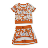 Girl wearing a short sleeve T-shirt and skirt set by Mini Rodeo, active girl’s team outfit with a bow detail on the top.