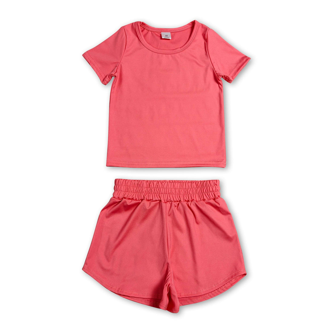 Girl wearing Mini Rodeo short sleeve peach top and shorts active set, perfect for kids&