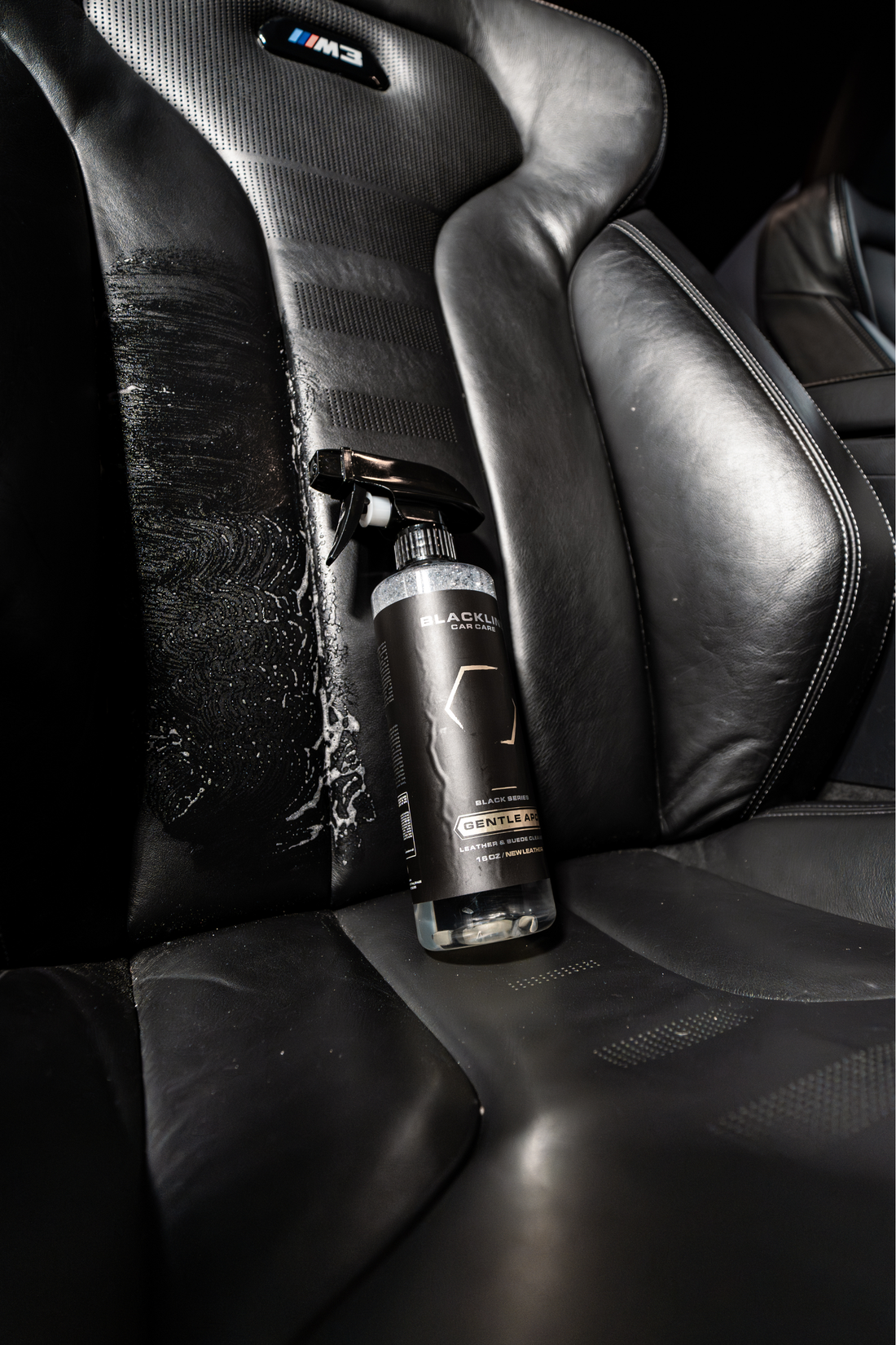 Blackline Car Care BLACKLINE® Gentle APC all-purpose cleaner cleaning a car seat with a spray bottle and microfiber cloth.