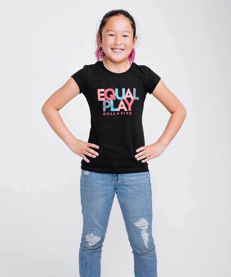 Girl wearing a black Equal Play T-shirt by Goal Five, casual lifestyle image showing front view of the girls&