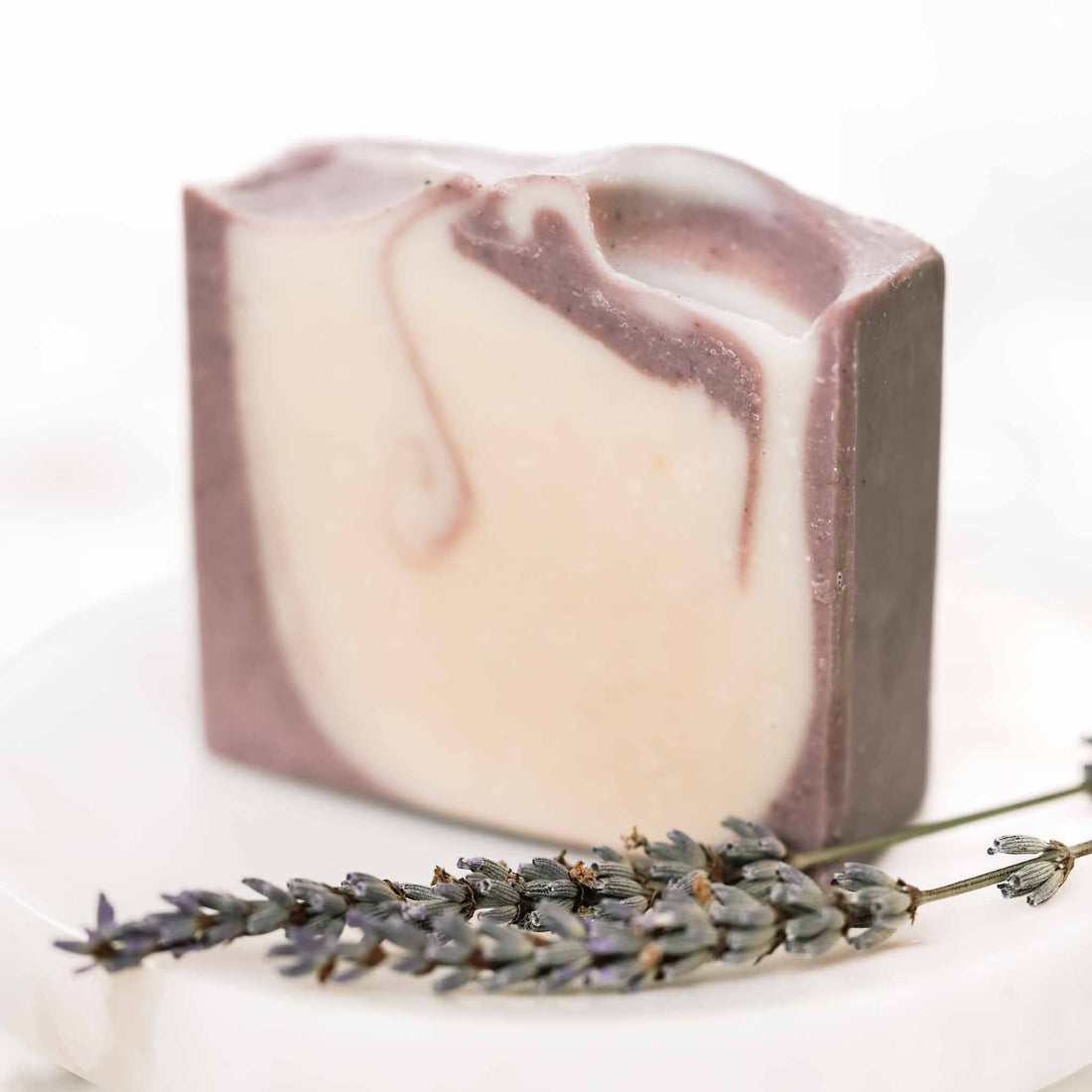 Lavender and mint scented handmade tallow and goat milk soap bar by Pretty Farm Girl, showing a soft purple and green soap on a wooden surface.