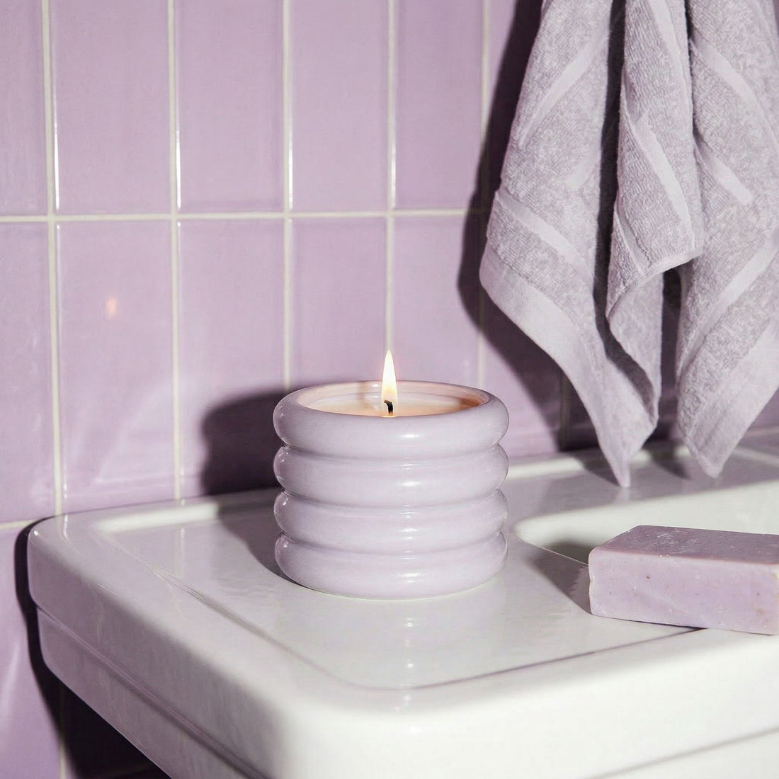 Lavender soy wax candle in a white ceramic holder by Italic, with a smooth, rounded design and a lit wick.
