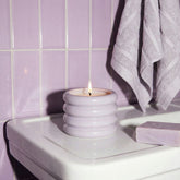 Lavender soy wax candle in a white ceramic holder by Italic, with a smooth, rounded design and a lit wick.