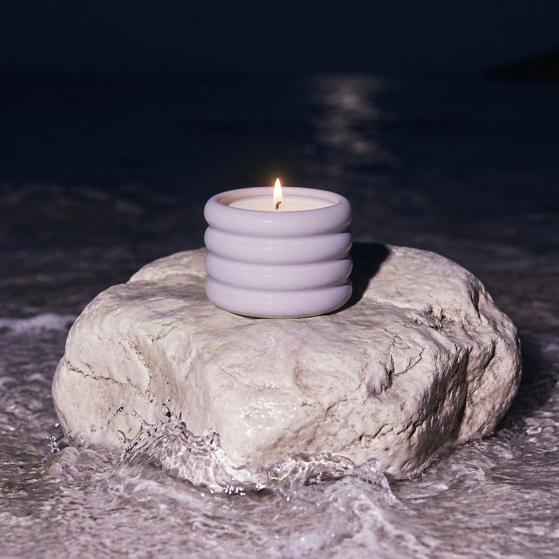 Lilac soy wax ceramic candle by Italic in a decorative ceramic holder, shown outdoors.